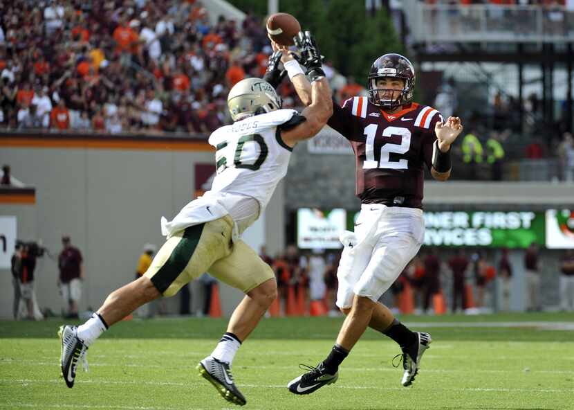 Quarterback Michael Brewer #12 of the Virginia Tech Hokies throws a pass over linebacker...