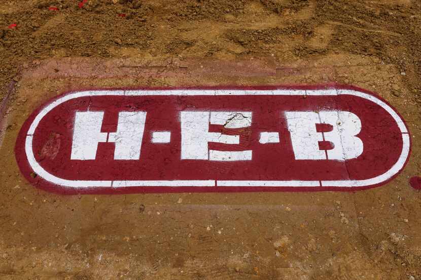 A logo was drawn in the dirt for the June 2021 groundbreaking ceremony for a Plano H-E-B...