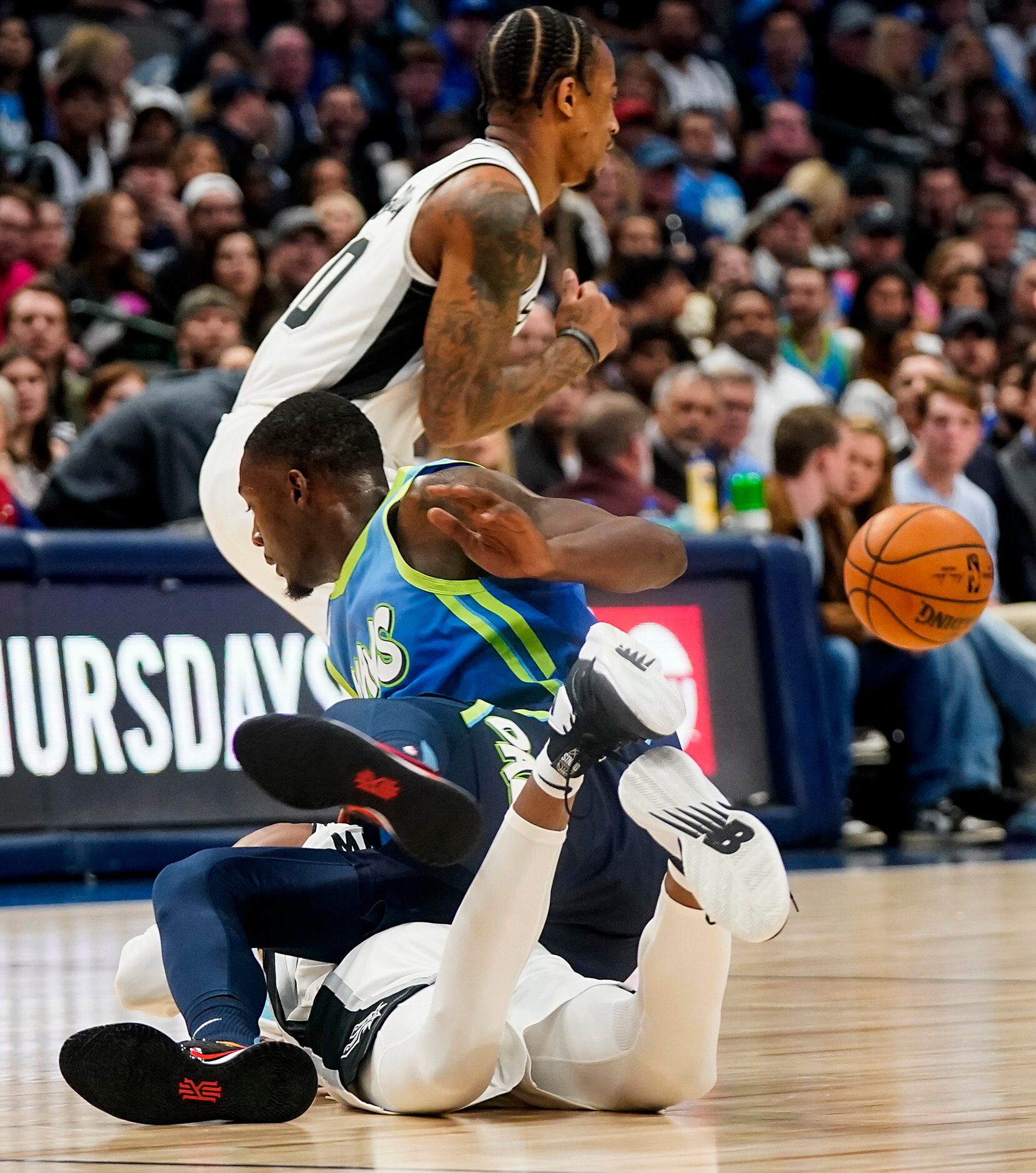 Dallas Mavericks forward Dorian Finney-Smith (10) tumbles over San Antonio Spurs guard...