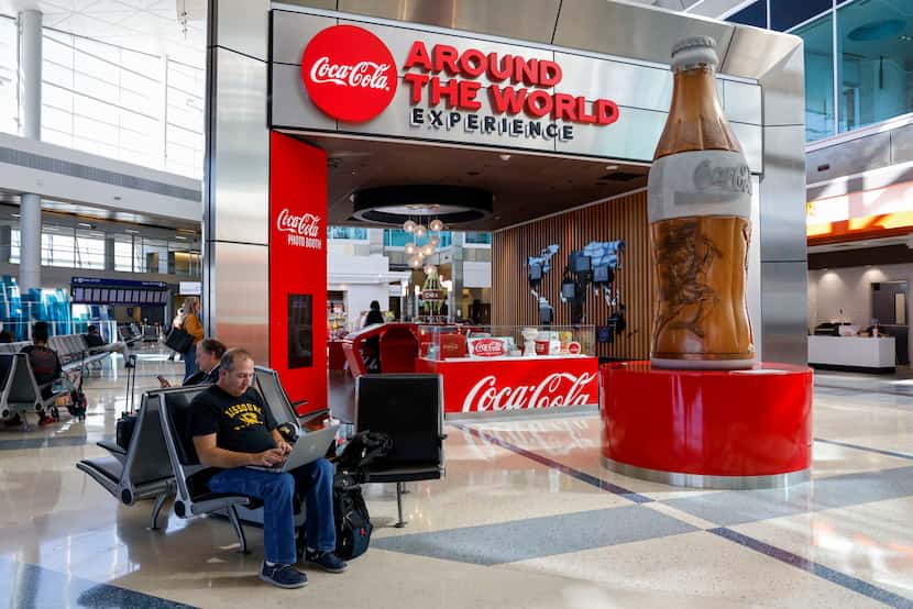 Travelers sit near the Coca-Cola Experience at Terminal D, Tuesday, Oct. 31, 2023, at DFW...
