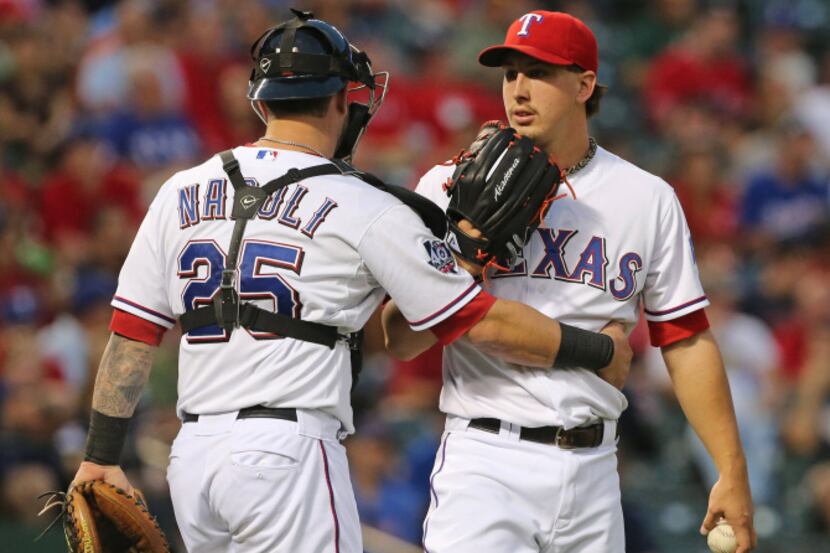 Texas catcher Mike Napoli talks with pitcher Derek Holland on the mound in the second inning...