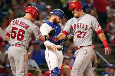 The Los Angeles Angels' Kole Calhoun (56) and Mike Trout (27) celebrate a home run by Trout...