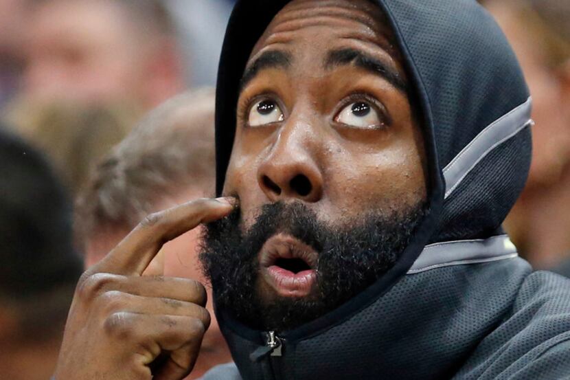 Houston Rockets guard James Harden wears the NBA-issued hooded warmup on the bench. (AP...