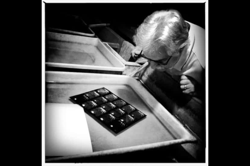 Robert Messina inspects a contact sheet in a tray of fixer after the lights are back on in...
