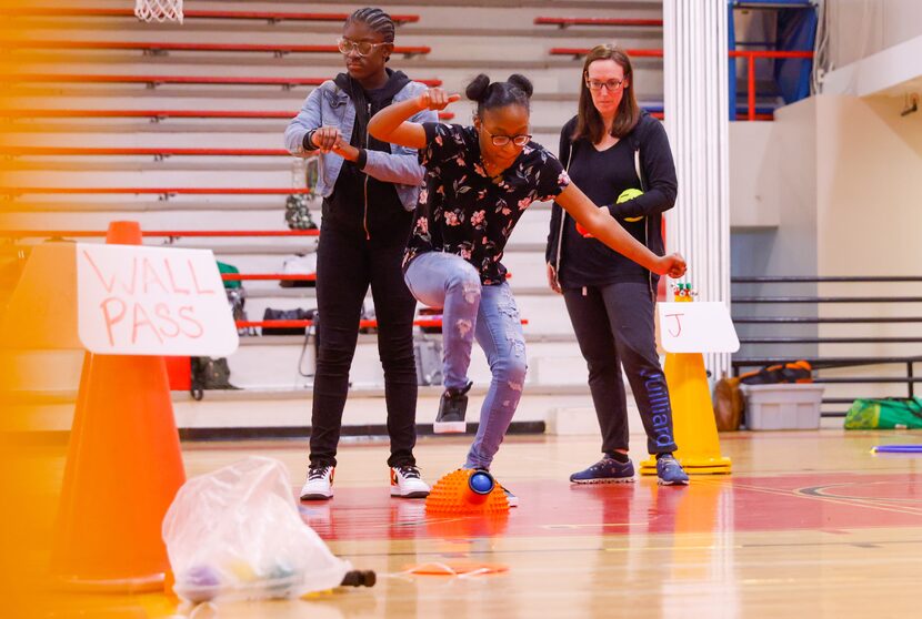 Angel Bracken (center), 18, stomps on a ball launcher during an adapted PE class for Dallas...