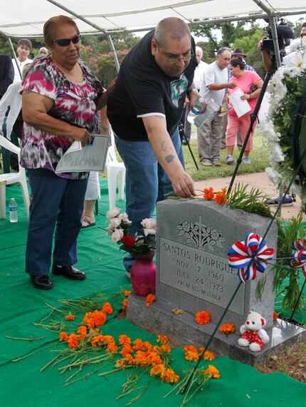 Bessie Rodriguez and her son David Rodriguez place a marigold on the grave of her son,...