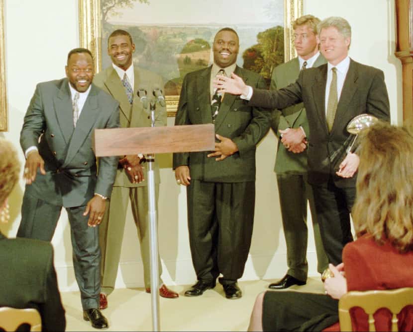 President Clinton, holding a replica of the Vince Lombardi, Super Bowl trophy, gestures...