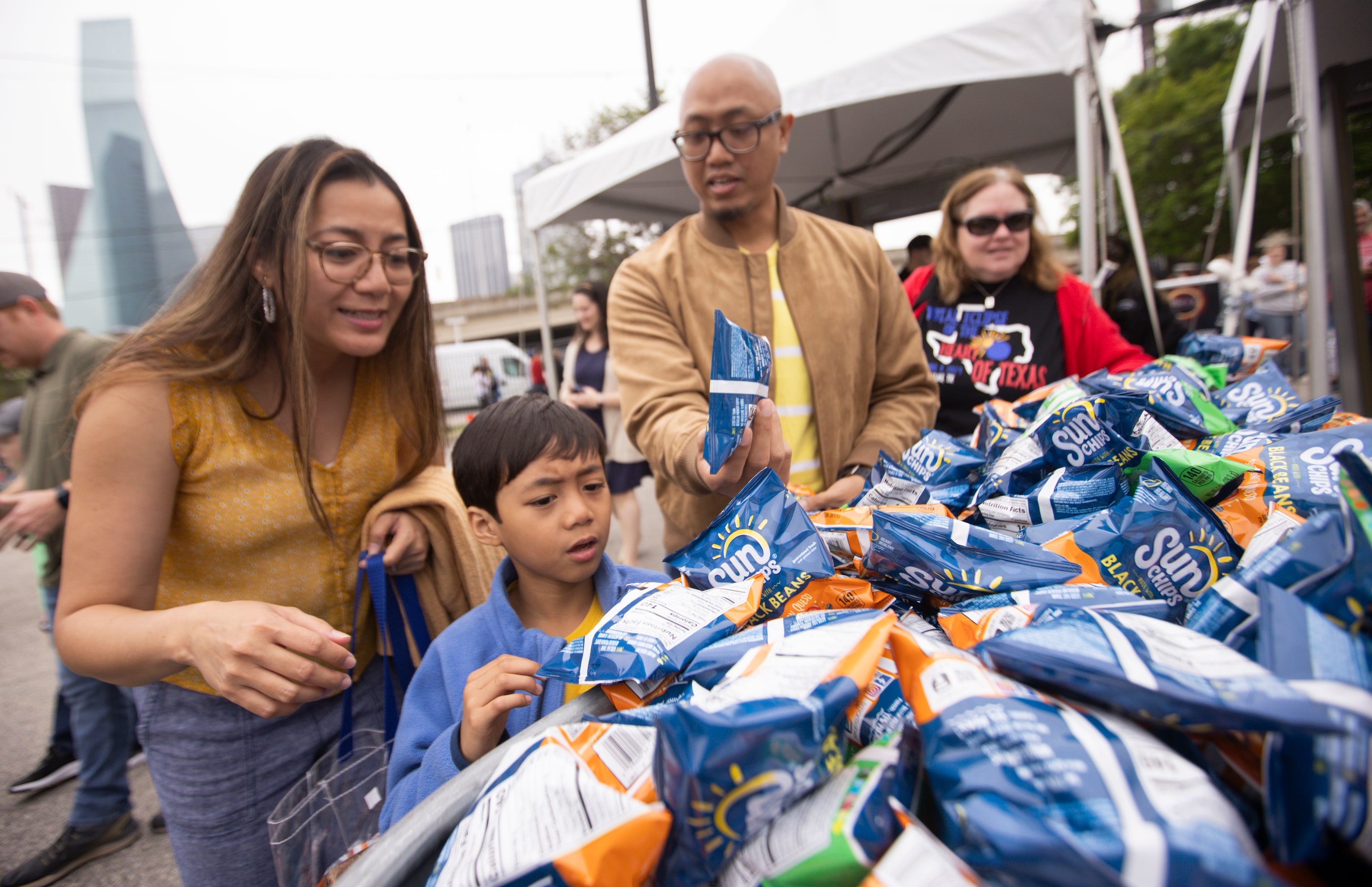 (From left) Ganda, Cale, 6, and Rex Paulino from Houston grab a pack of Sun Chips as they...