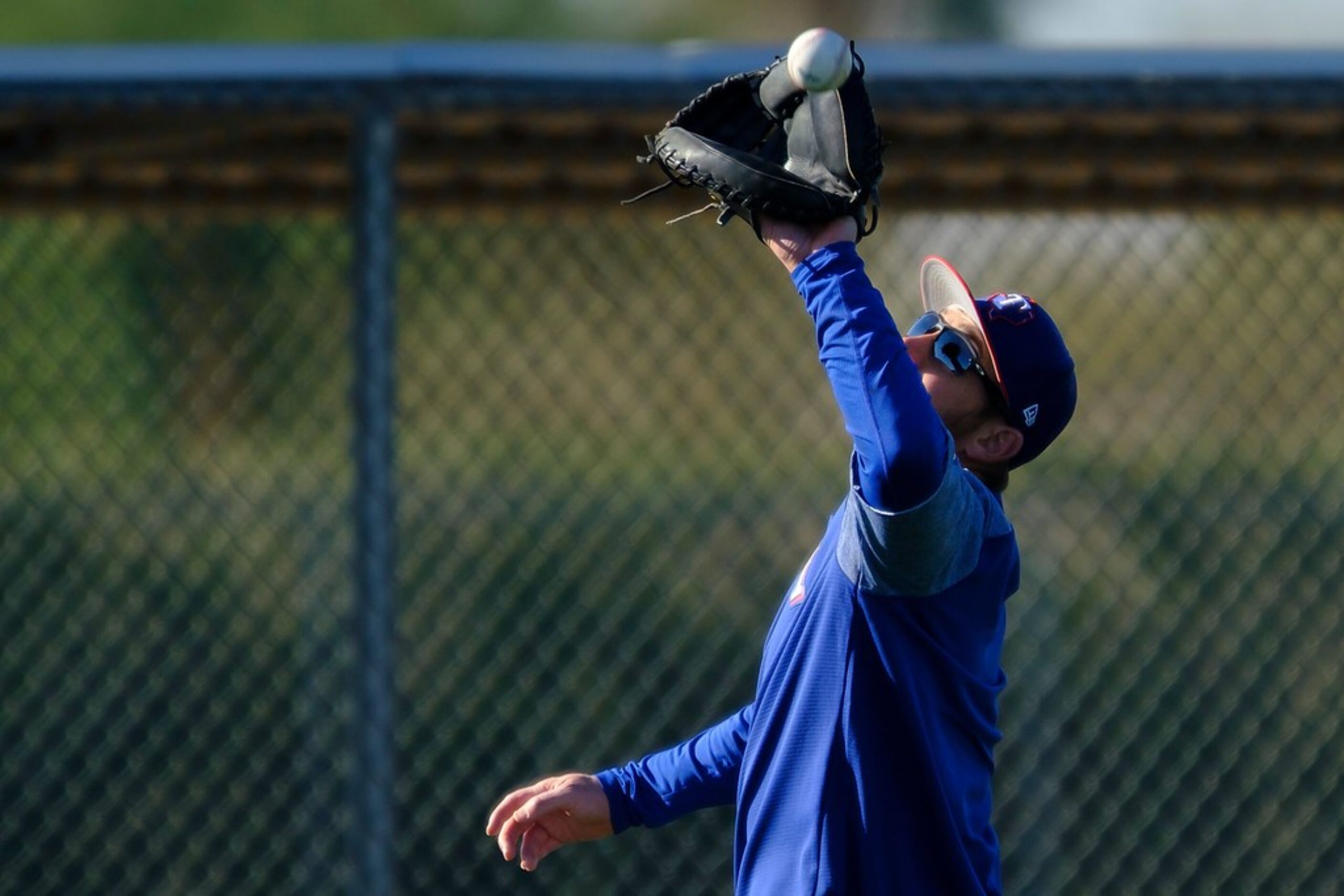 Texas Rangers catcher Jeff Mathis reaches for a ball tossed his way during a spring training...