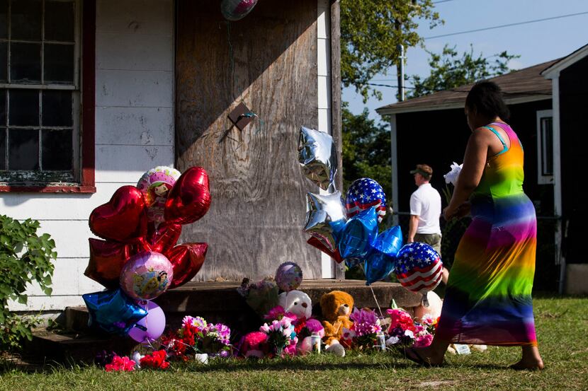 Adrian Moseley, of Dallas, plants a flower at a memorial as balloons and flowers wave in the...