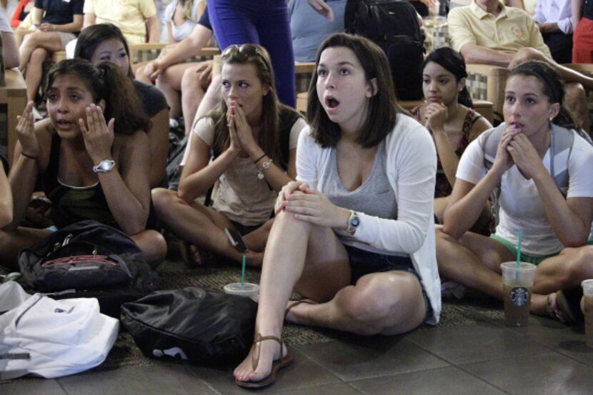 Laura Lovins (center), a Penn State sophomore,  reacts to a televised report on the school's...
