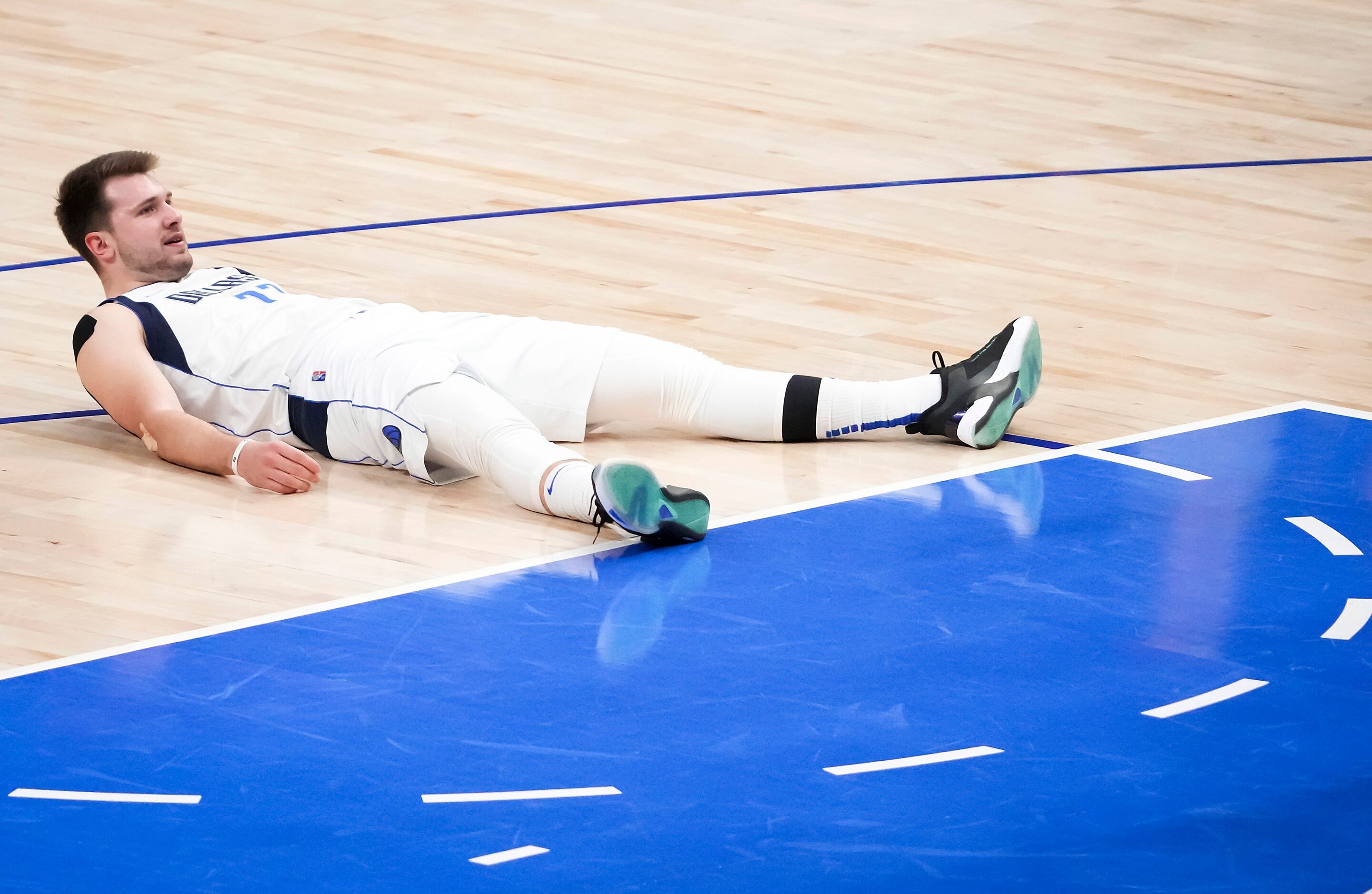 Dallas Mavericks guard Luka Doncic lies on the floor after being knocked backwards on a...