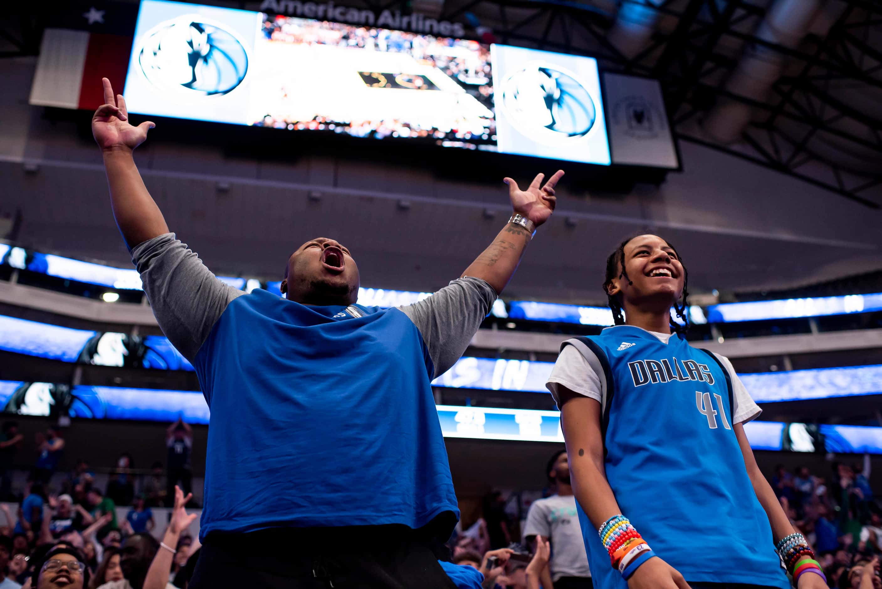 From left, Reggie Ellis exclaims after the Mavericks hit a three pointer alongside his son,...