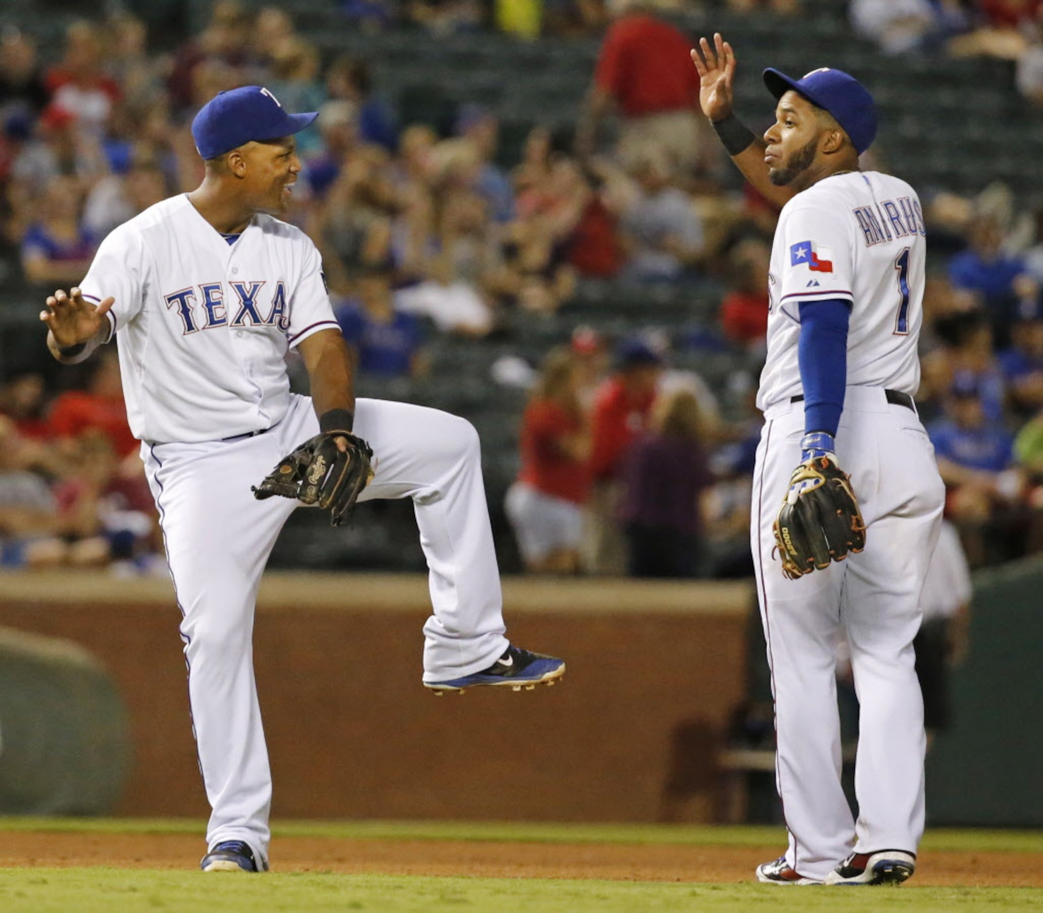 Third baseman Adrian Beltre and shortstop Elvis Andrus gesture as they talk in the infield...