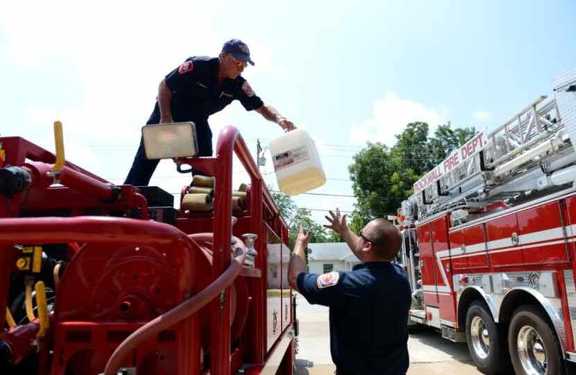 
Craig Merritt (left), a part-time volunteer firefighter for the city of Rockwall, hands a...