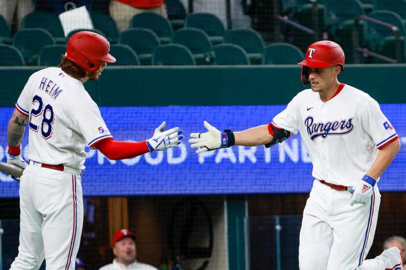 Texas Rangers shortstop Corey Seager (5) high-fives Texas Rangers catcher Jonah Heim (28)...