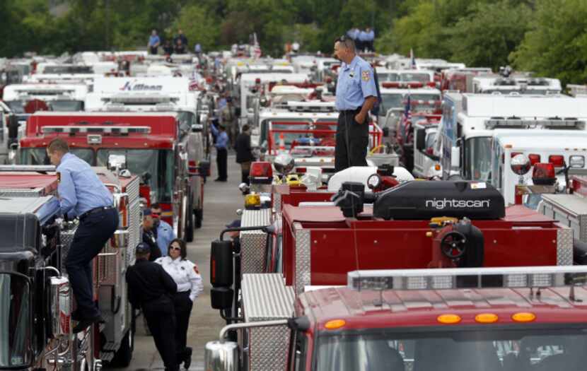 Firefighters and trucks gather in a staging area Thursday in West before a procession to...