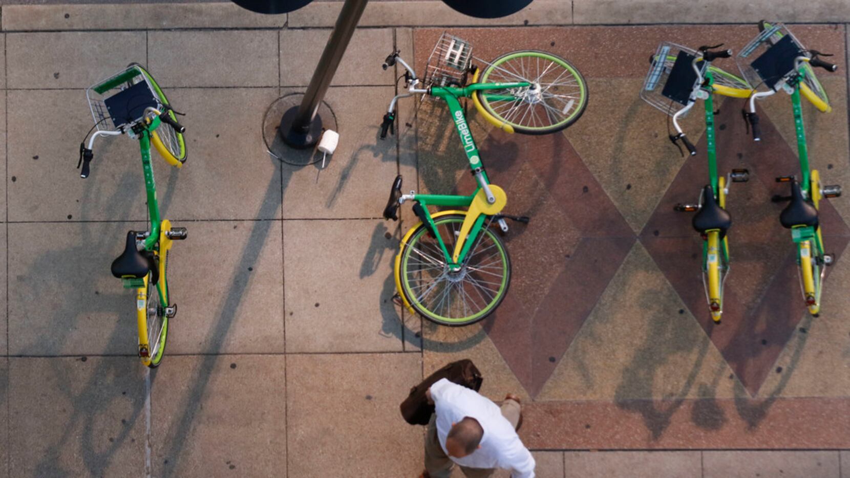 A pedestrian walks around a fallen rental bike at the corner of Harwood and Elm Streets in...
