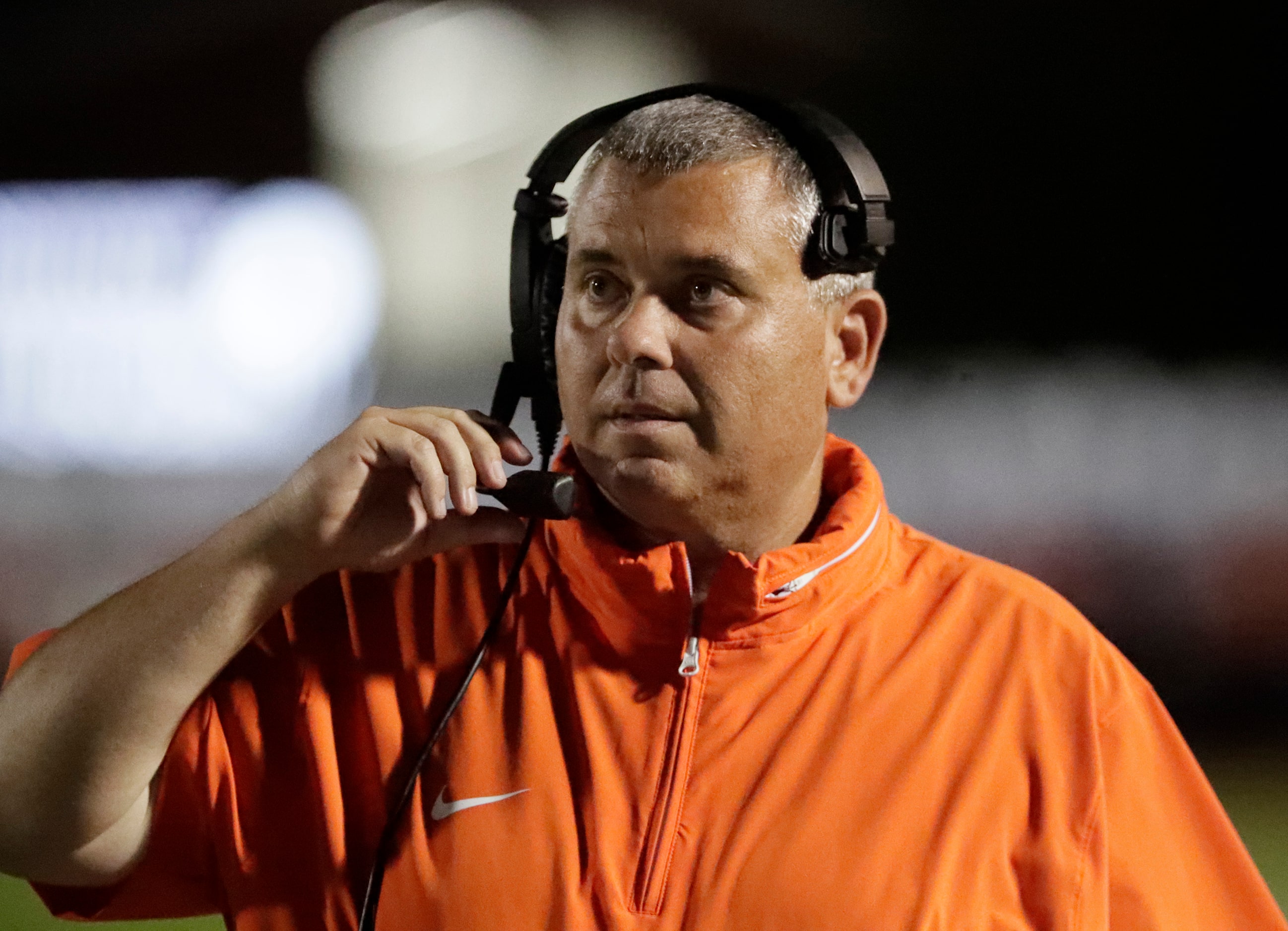 Wakeland High School head coach Chan Isom talks on his headset during the first half as...