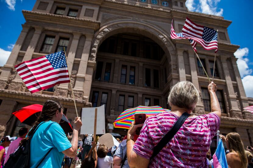 Protestors wave American flags during a One Texas Resistance rally on the south steps of the...