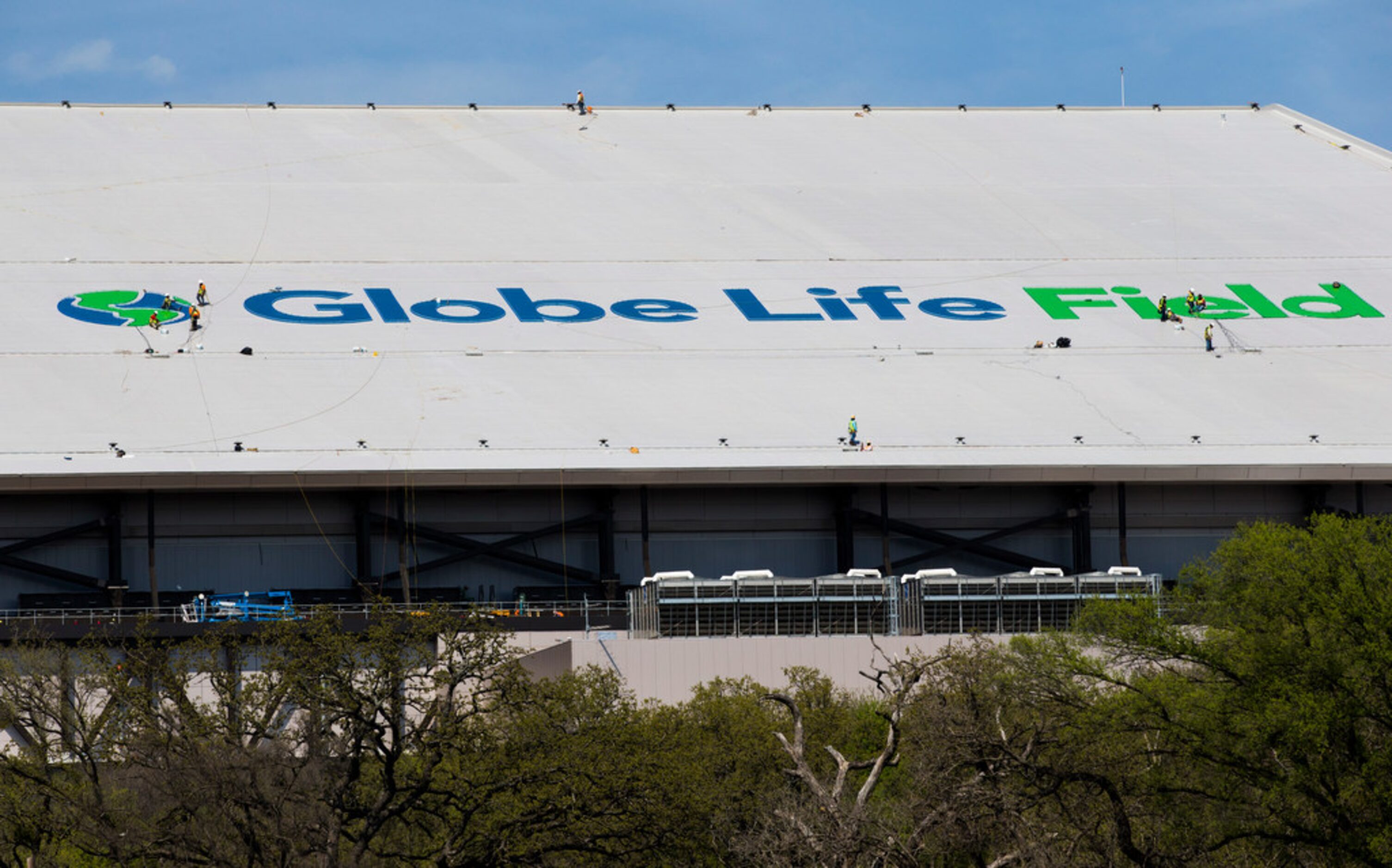 Crews work on a Globe Life Field logo on the roof of the stadium during an open house for...