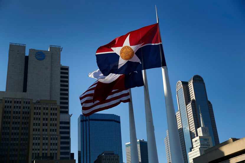 The city of Dallas flag flies alongside the Texas and U.S. flags outside Dallas City Hall.