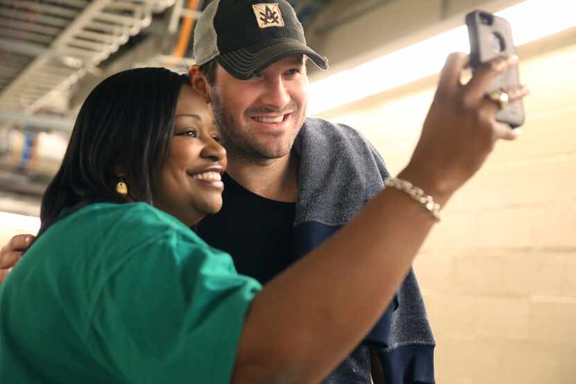 Dallas Cowboys quarterback Tony Romo, right, makes a cell phone photos with a fan in the...