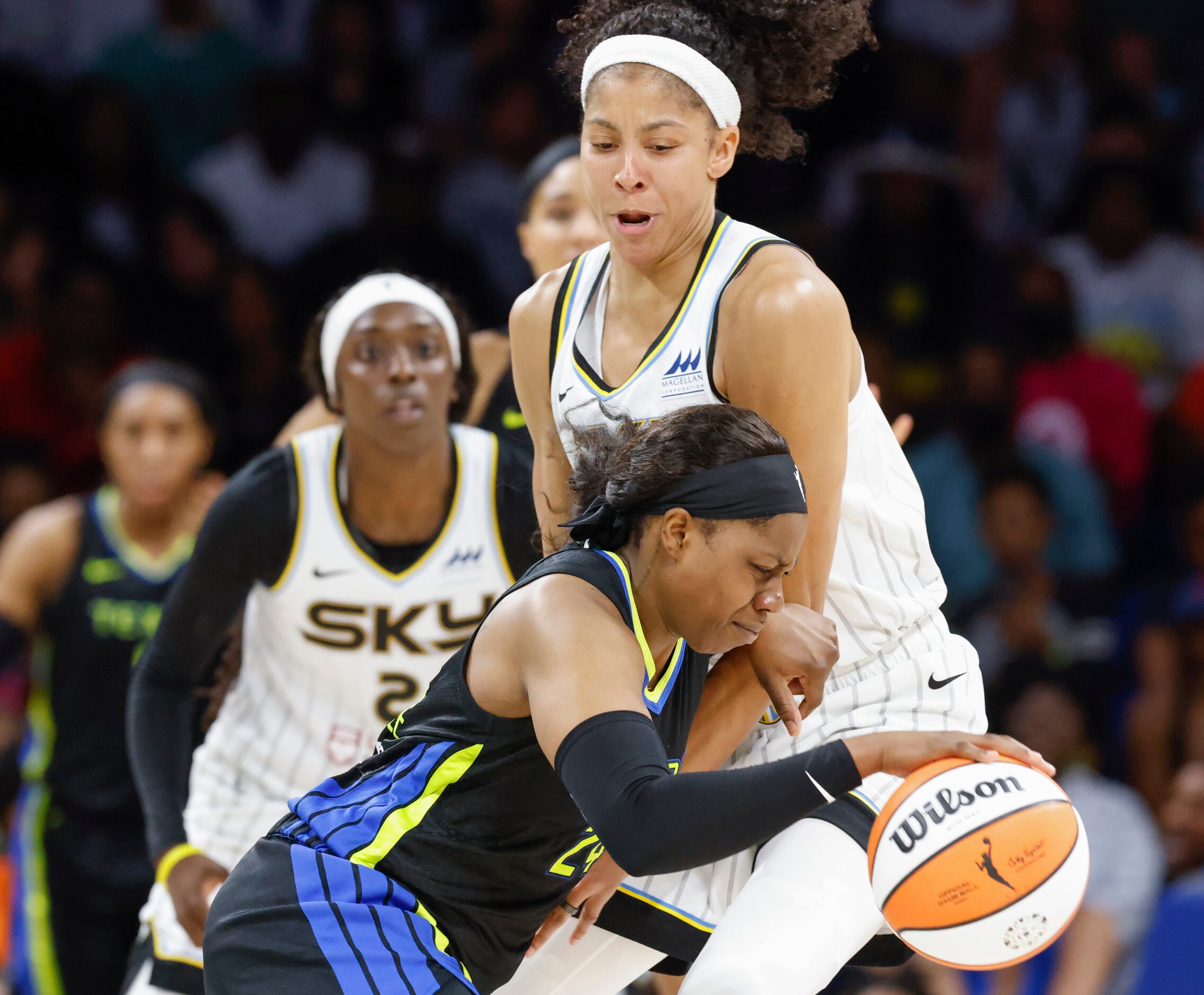 Dallas Wings guard Arike Ogunbowale, front, dribbles past Chicago Sky forward Candace Parker...