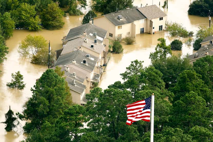 The U.S. flag flies before flooded condo buildings sitting in the the overflowing San...