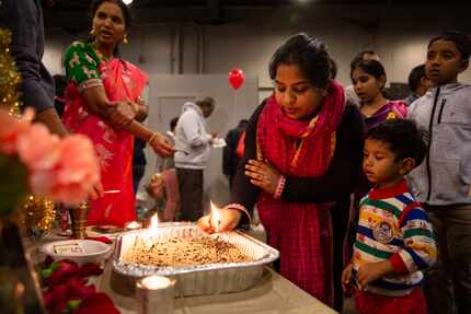 Sonam Modi and her son Kush Gupta place a light at a traditional altar during Diwali Mela on...