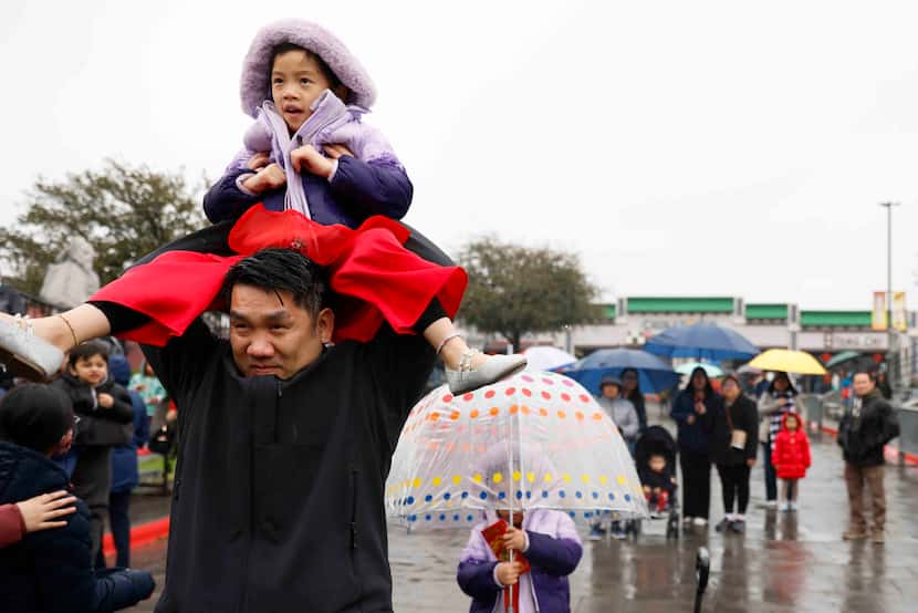 Chris Lam lifts up her daughter Sophia, 7, to get a peek of the cultural show on the main...
