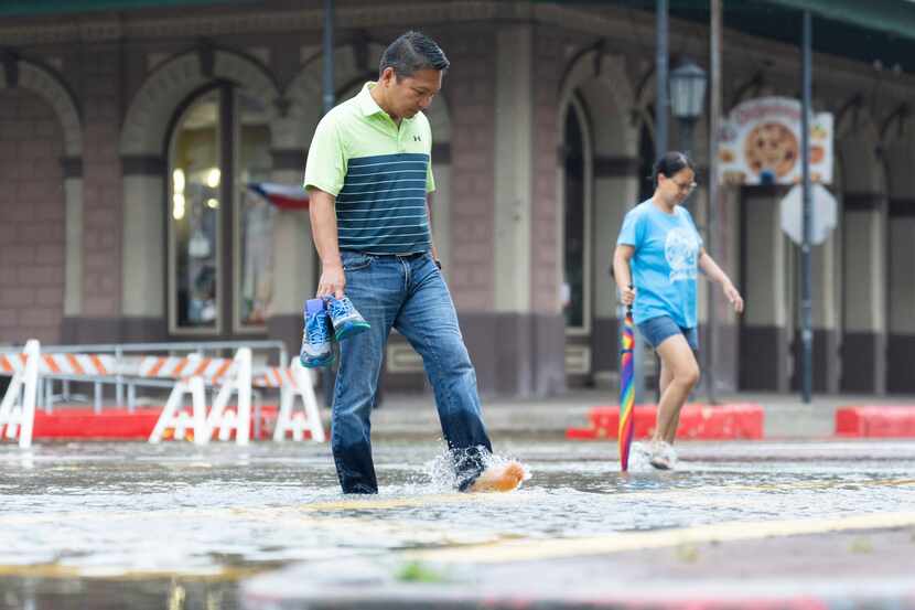 Roy Quiroz and his wife, Minda, cross a flooded section of The Strand near Kempner Street as...