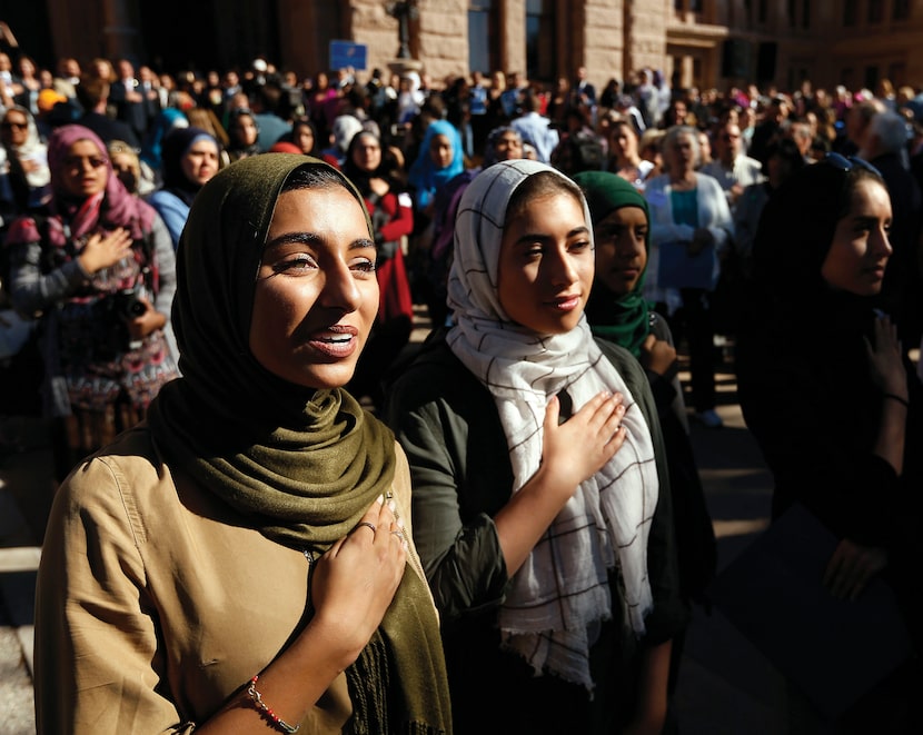 Hiba Loya and Donia Kased, both of Houston, join in the singing of the national anthem...