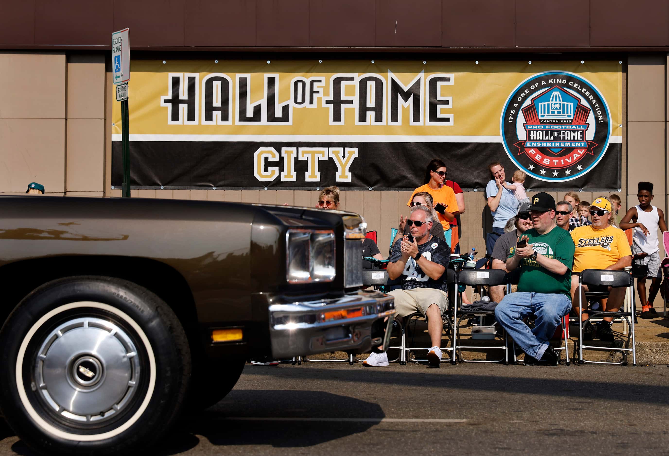NFL football fans watch as Pro Football Hall of Fame members pass by in classic cars during...