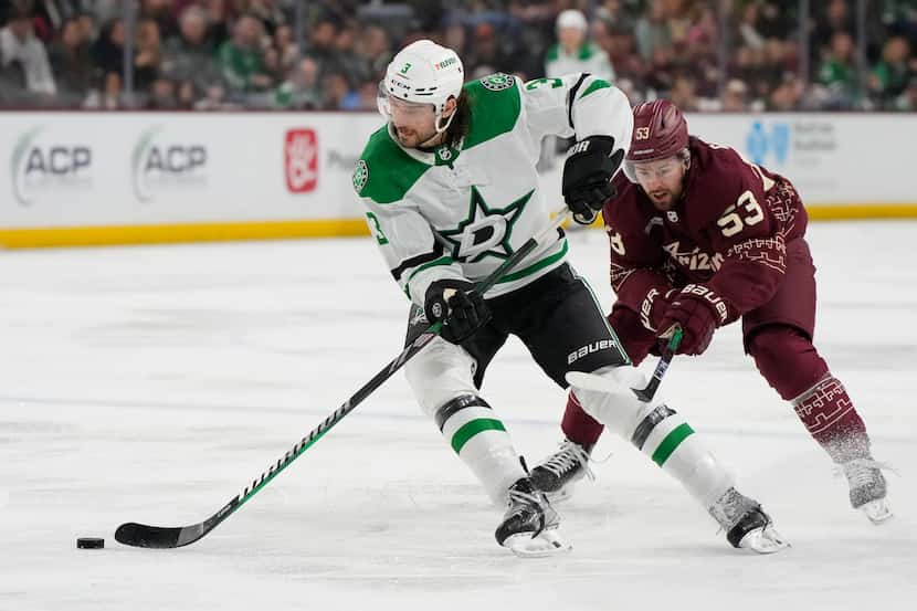 Dallas Stars defenseman Chris Tanev (3) shields the puck from Arizona Coyotes left wing...