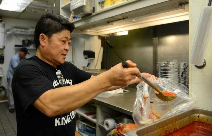 
Lap Duong pours cajun sauce onto crab in the kitchen of Louisiana King Crab on Main Street...