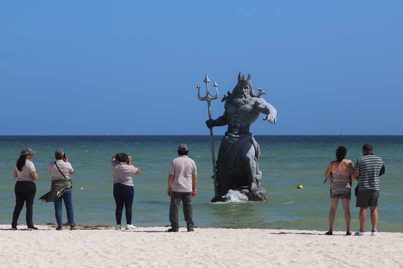 Turistas toman fotografías de la escultura de Poseidón antes de la llegada del huracán Beryl...