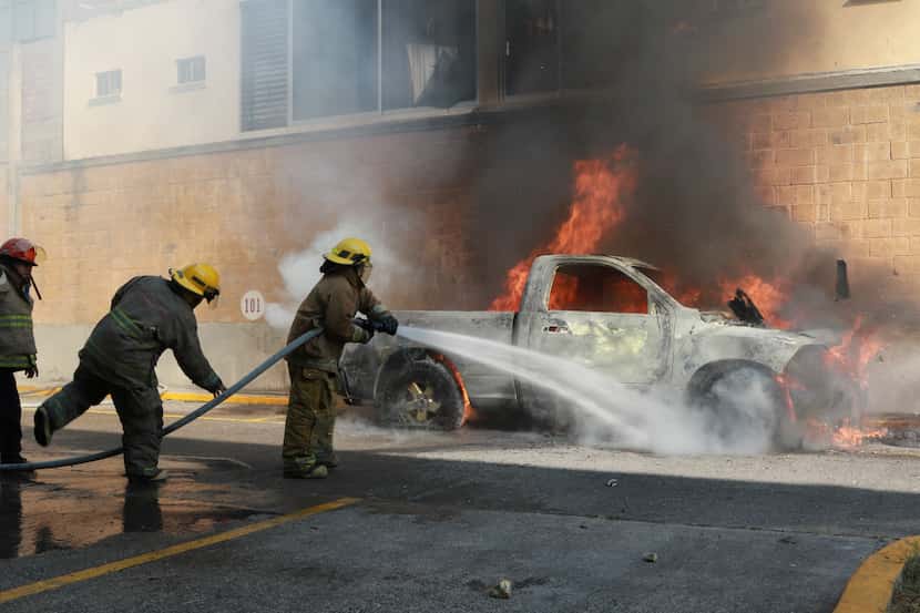 Bomberos extinguen el fuego en una camioneta incendiada por un grupo de manifestantes que...