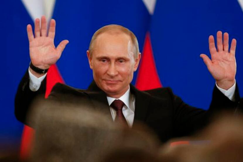 
Russian President Vladimir Putin gestures in triumph after signing a treaty to incorporate...