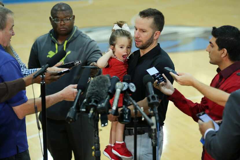 Dallas Mavericks point guard J.J. Barea holds his daughter Paulina Barea while speaking to...