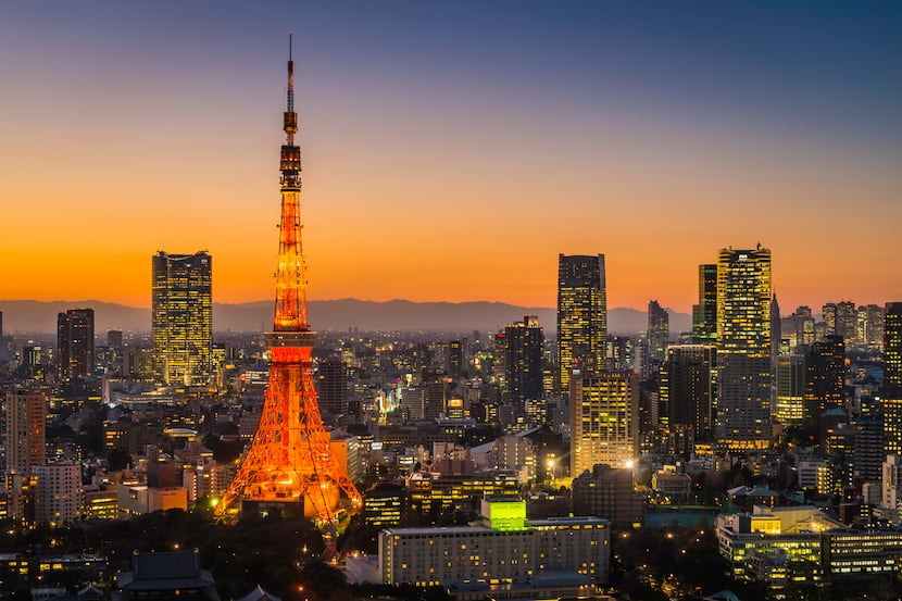The iconic spire of Tokyo Tower spotlit above the twinkling lights and skyscrapers of...