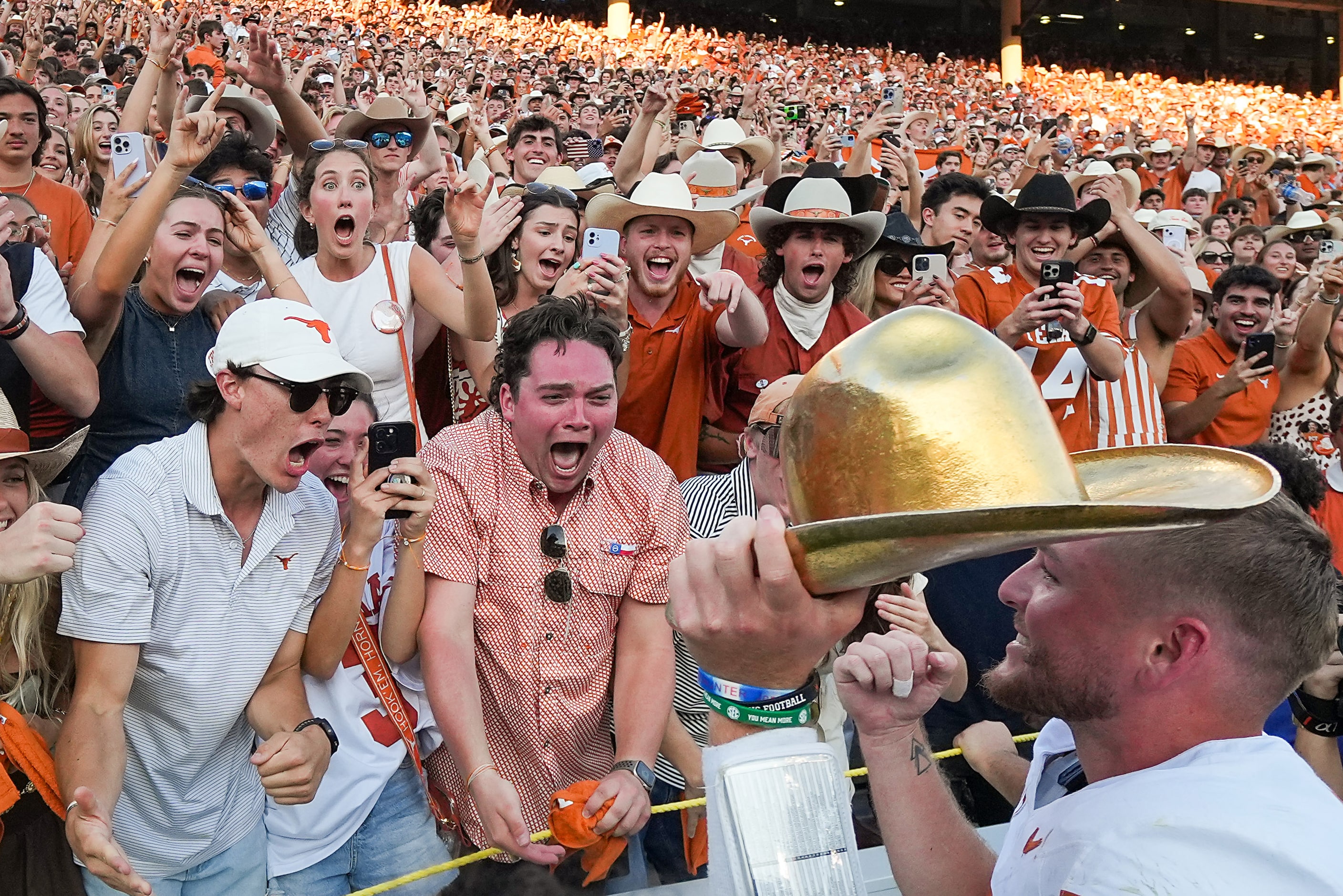 Texas quarterback Quinn Ewers shows the Golden Hat Trophy to fan after a 34-3 victory over...