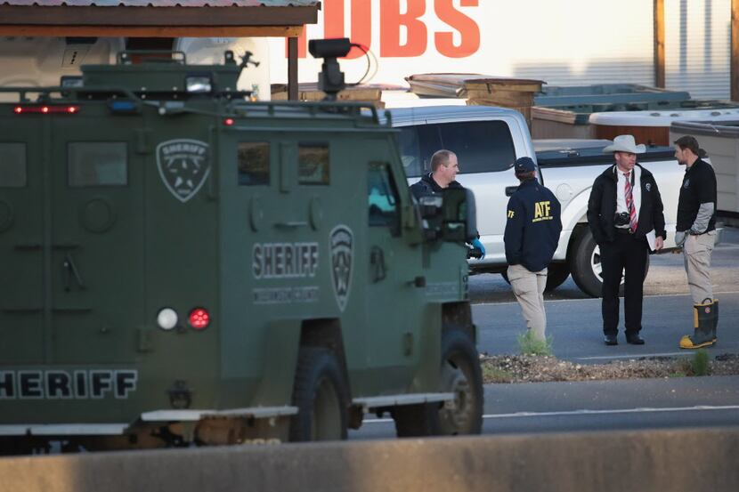 Law enforcement officials search for evidence at the location where the suspected package...