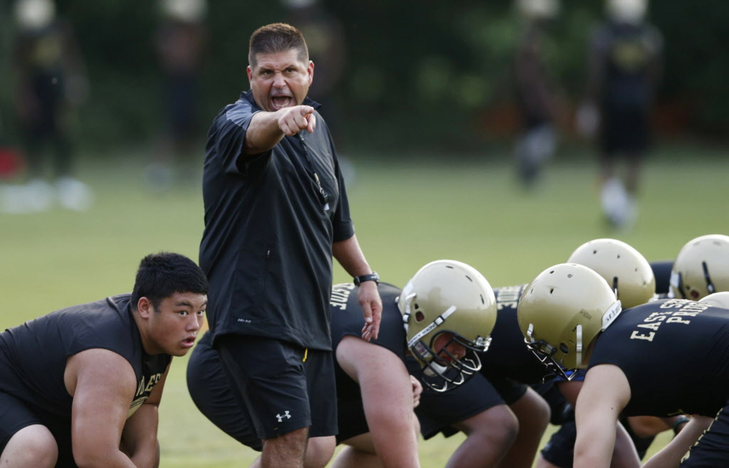 Plano East head coach Joey McCullough instructs players during the first day of football...