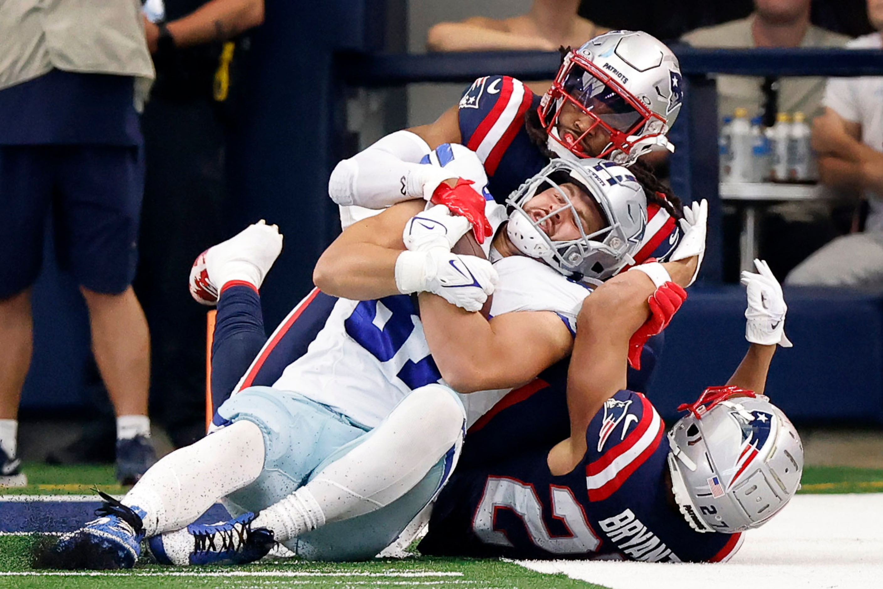 Dallas Cowboys tight end Jake Ferguson (87) is rolled up by New England Patriots safety Kyle...