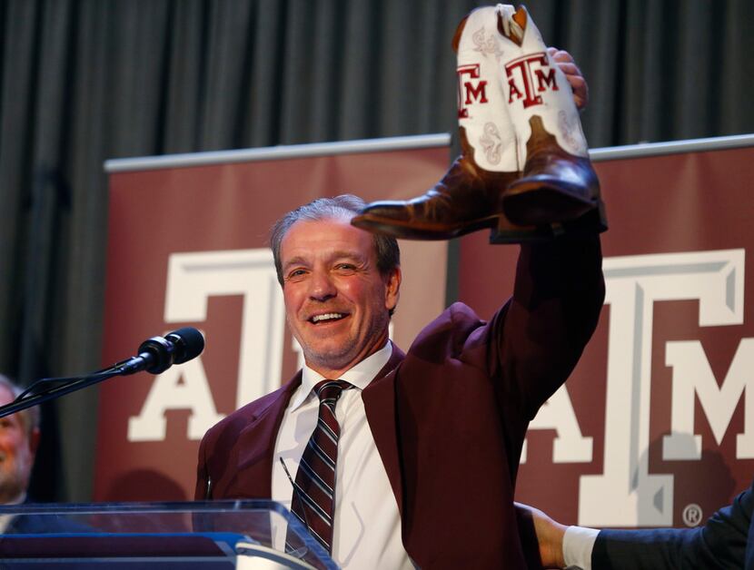Texas A&M's new coach Jimbo Fisher shows of his new boots during a press conference at Kyle...
