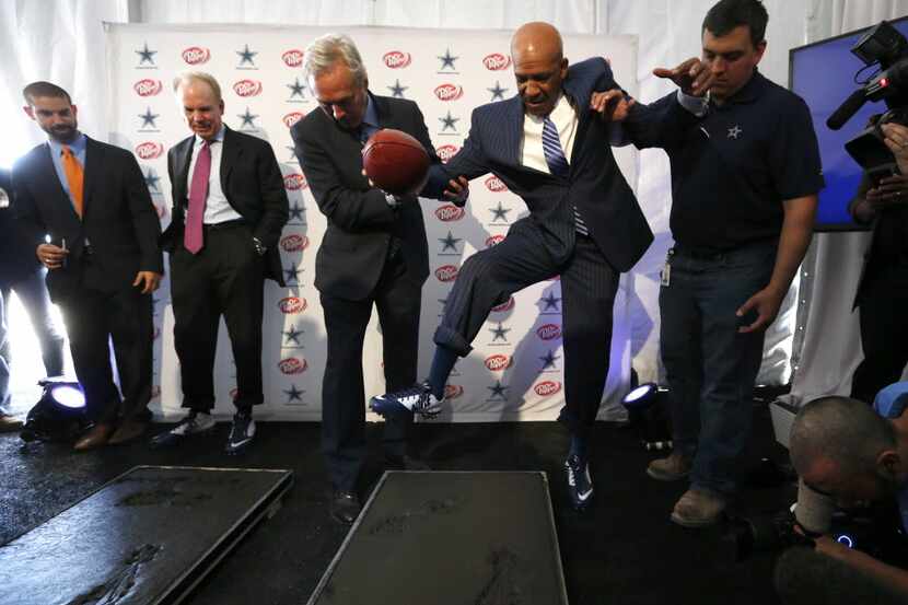 Dallas Cowboys Drew Pearson is helped out of cement during a press conference announcing the...