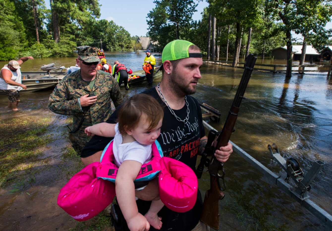 Robert Burge holds his daughter, Chevy Wayne, 1, and his rifle as Marines and members of a...