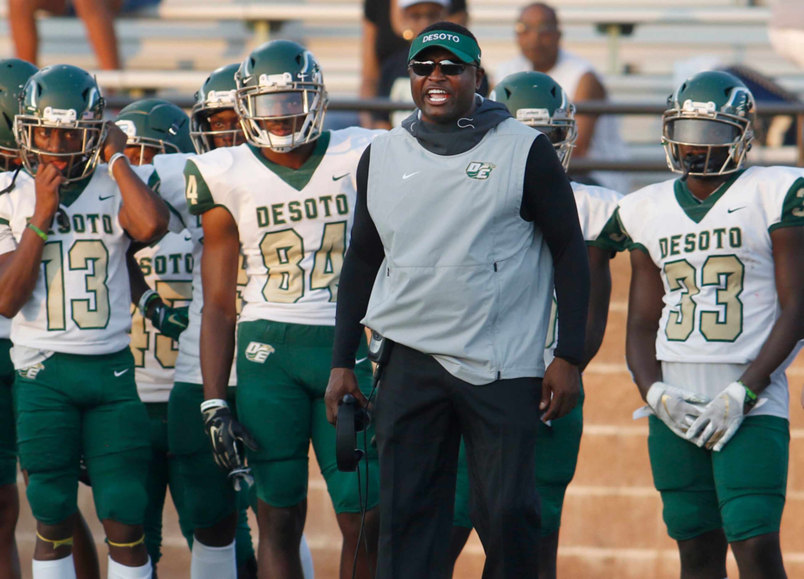 Surrounded by Eagles players, DeSoto head coach Claude Mathis closely follows first quarter...