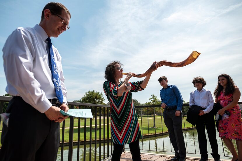 Adena Cytron-Walker, center, blows into a ram's horn, traditionally known as the Shofar, as...